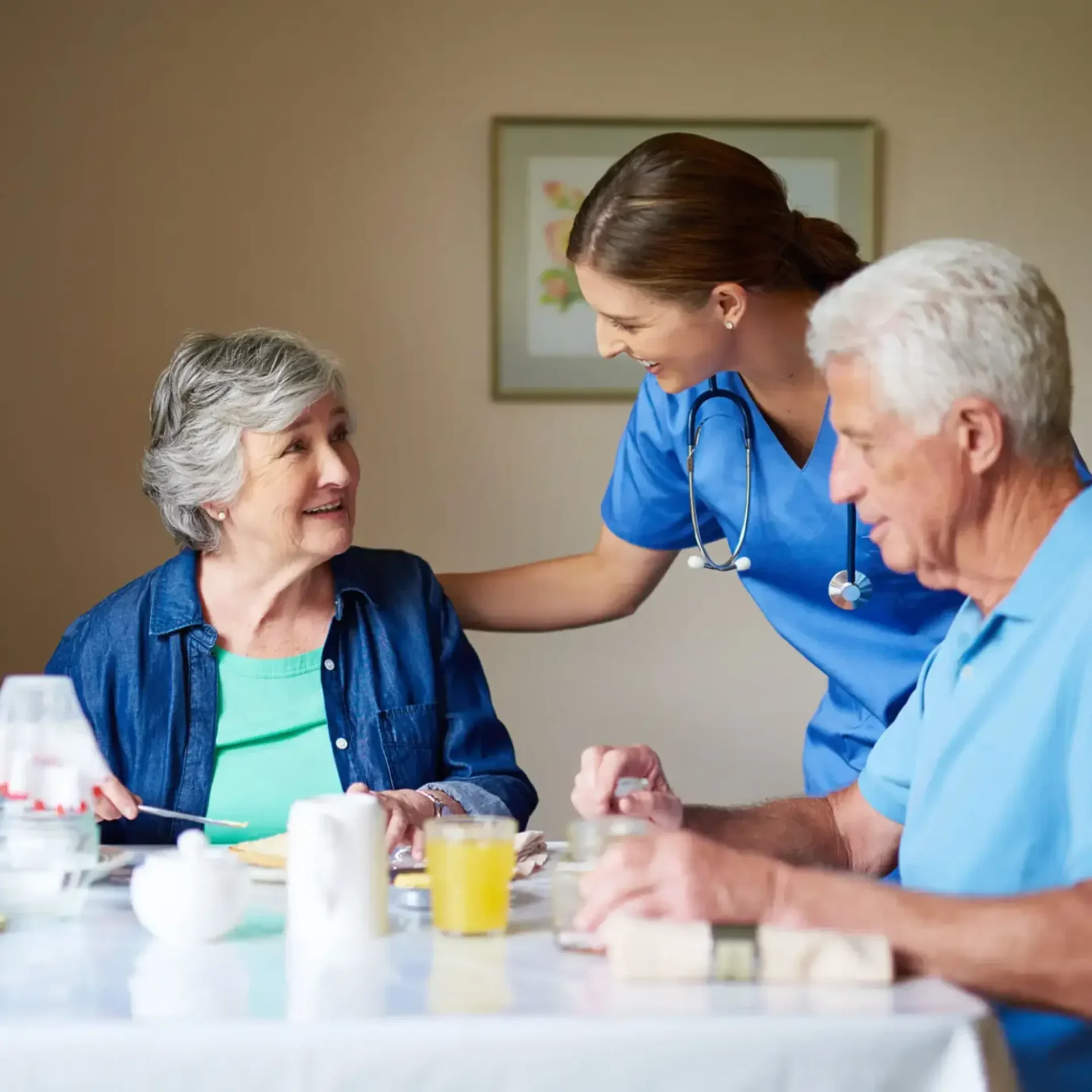 A nurse and two elderly people sitting at a table.